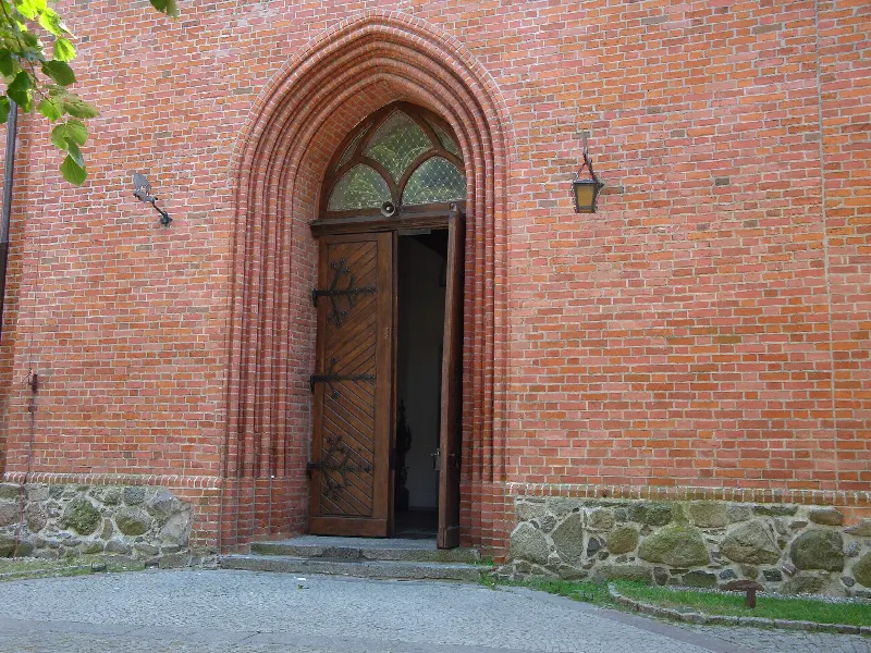 Ostrołukowy ceglany portal fary w Pucku z kamiennym cokołem z granitowych ciosów