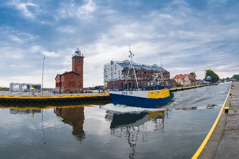 Kuter wpływający kanałem portowym do Darłówka obok latarni morskiej