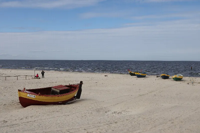 Łodzie rybackie na szerokiej piaszczystej plaży w Jantarze