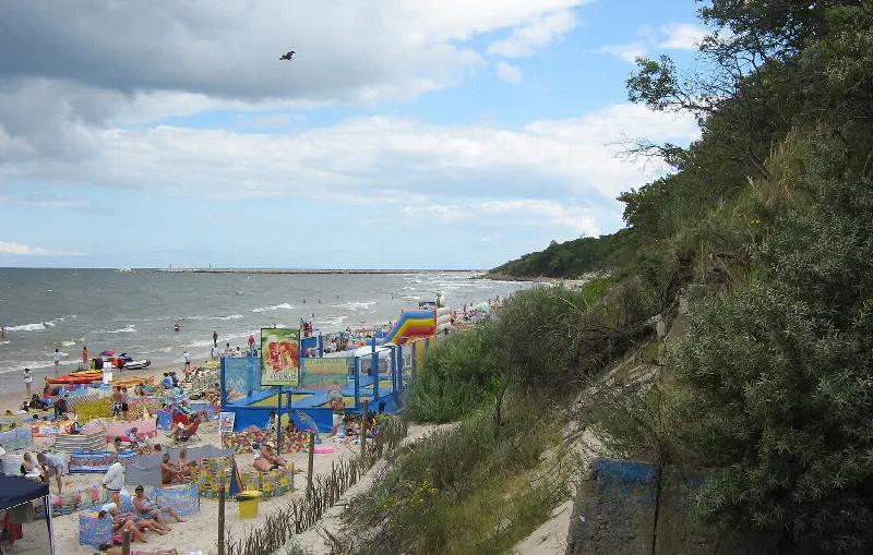 Plaża Zachodnia w Kołobrzegu z lotu ptaka: piasek z parasolami, zejście i porośnięta wydma