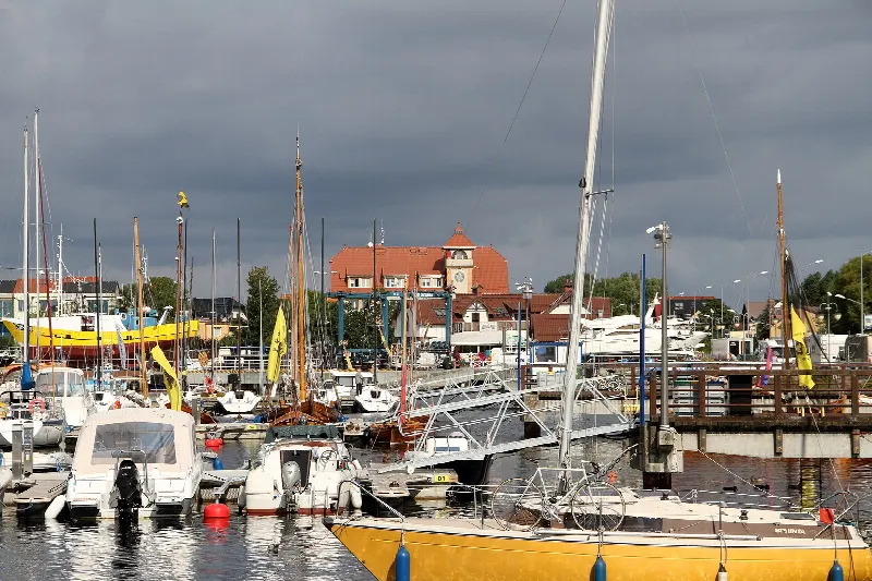 Port jachtowy i rybacki w Jastarni z jachtami przy pomostach i zabudową miasteczka w tle