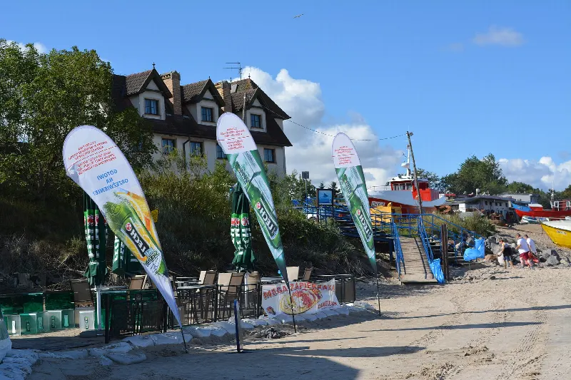 Zejście na szeroką plażę w Chłopach z wydmą i zabudową wsi w tle